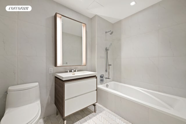 full bathroom with vanity, tile walls, toilet, and tiled shower / bath