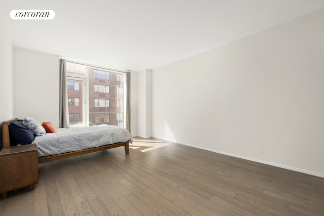 bedroom featuring visible vents, expansive windows, baseboards, and hardwood / wood-style floors