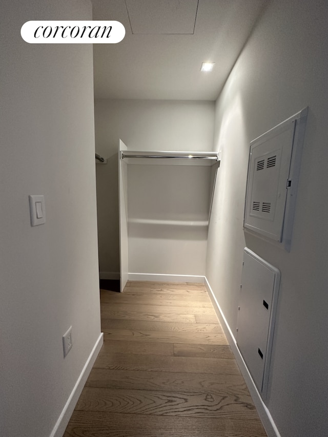 corridor with an upstairs landing, baseboards, and wood finished floors