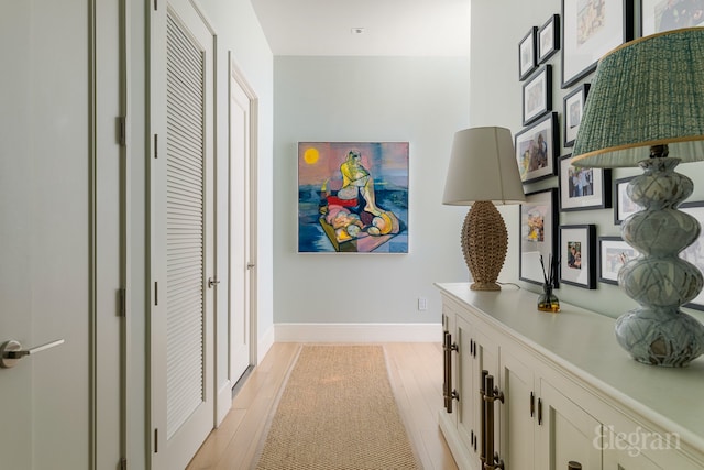 corridor featuring light wood-style flooring and baseboards