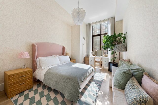 bedroom with an inviting chandelier, wood finished floors, and wallpapered walls