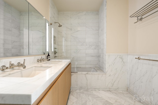 full bath with double vanity, tiled shower / bath combo, marble finish floor, tile walls, and a sink