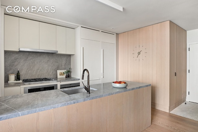 kitchen with a sink, under cabinet range hood, tasteful backsplash, wall oven, and stainless steel gas stovetop