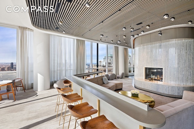 living room featuring a city view, a glass covered fireplace, and carpet flooring