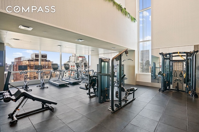 gym with visible vents, a view of city, and a wall of windows