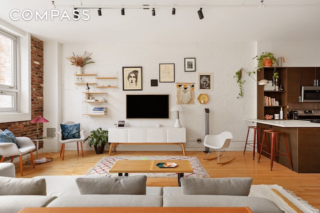 living area featuring brick wall and wood finished floors