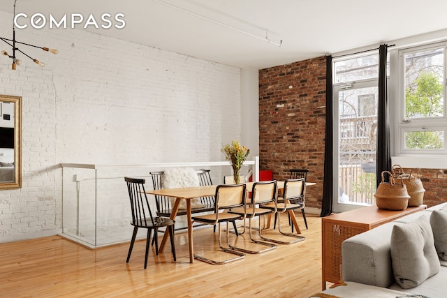 dining room featuring wood finished floors and brick wall