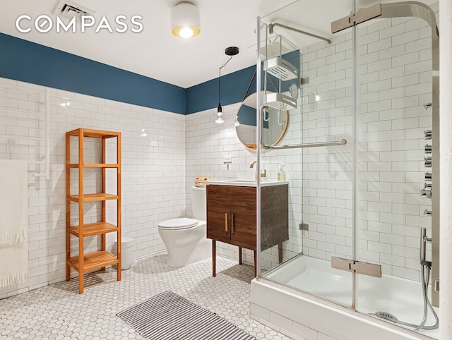 full bath with tile patterned floors, toilet, tile walls, a shower stall, and vanity