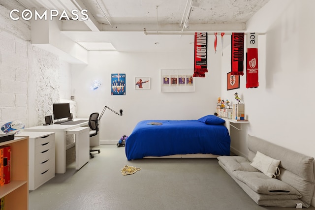 bedroom featuring concrete block wall and finished concrete flooring