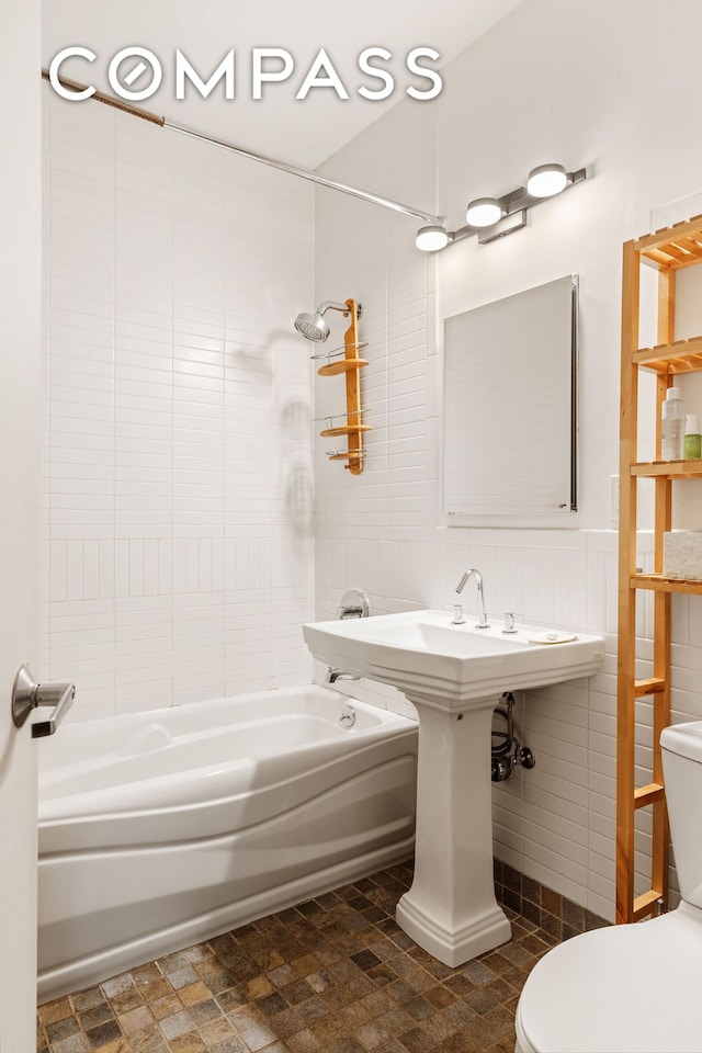 bathroom with shower / bathing tub combination, toilet, and tile walls