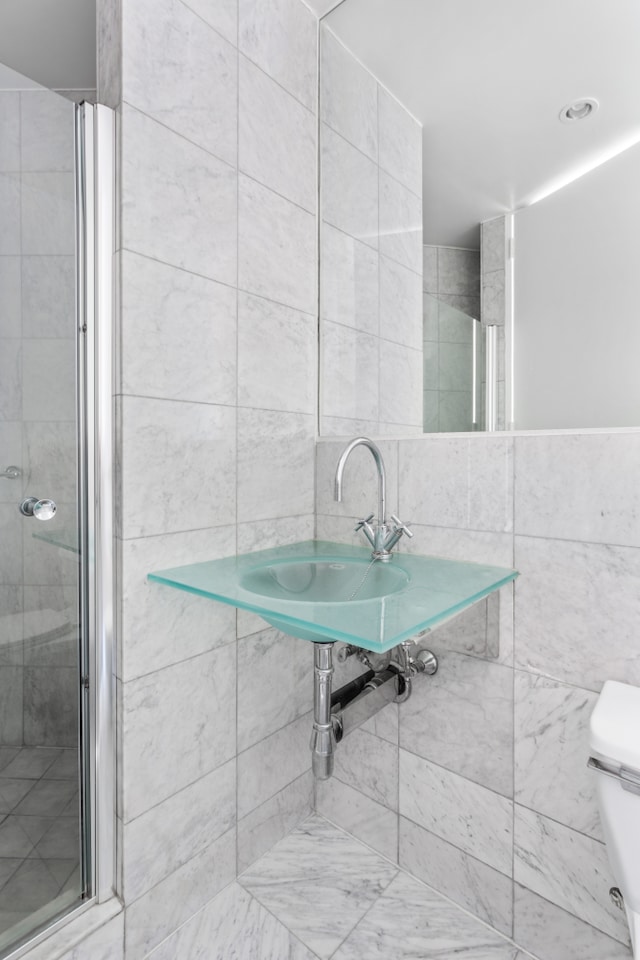 full bathroom featuring a shower stall, tile walls, and toilet