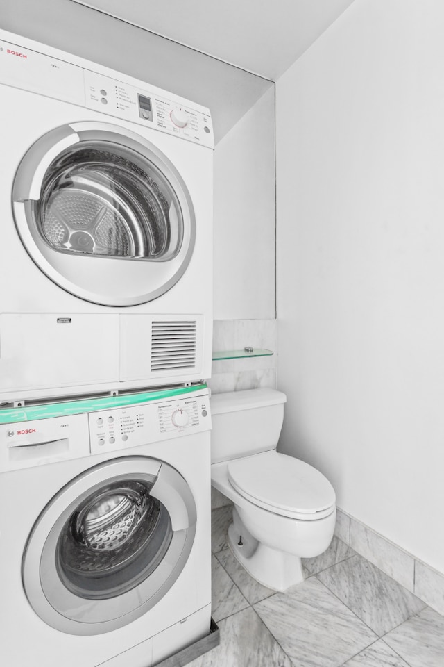 146 W 57th St Unit 34A, New York City, NY 10019 - bathroom featuring stacked washer and clothes dryer and marble look tiles