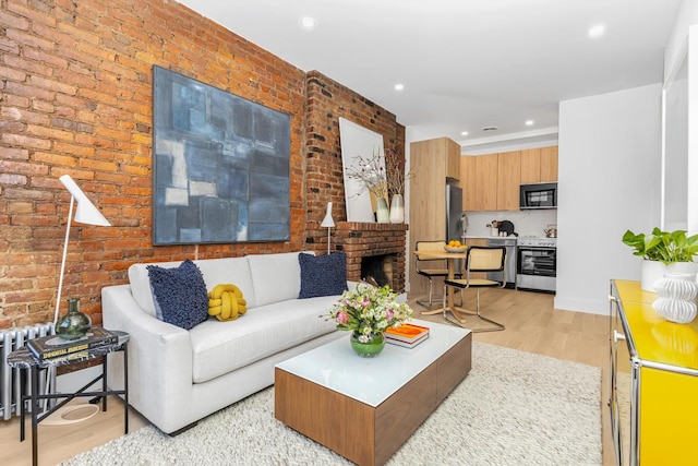 living room featuring light wood-style flooring, brick wall, and radiator heating unit