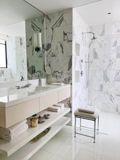 full bathroom with double vanity, tile walls, a marble finish shower, and a sink