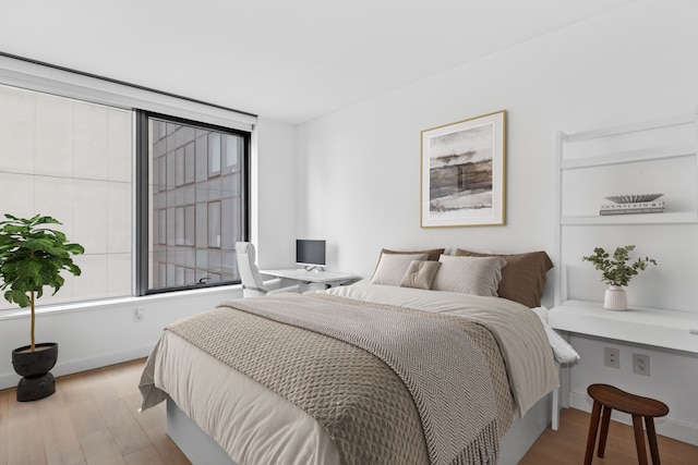 bedroom with multiple windows, baseboards, and wood finished floors