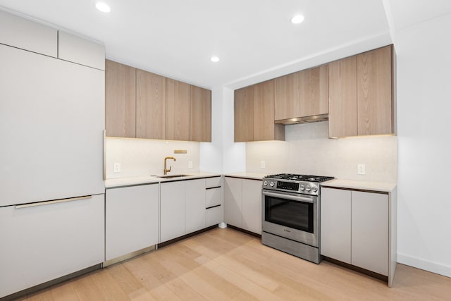 kitchen featuring a sink, white fridge, light countertops, modern cabinets, and stainless steel gas stove