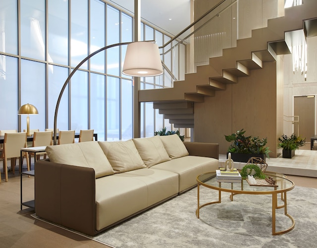 living room with stairway, a towering ceiling, and expansive windows