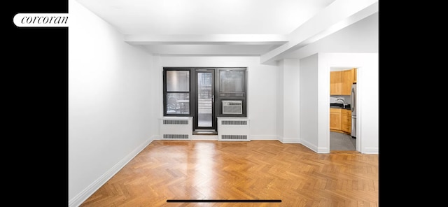 unfurnished room with baseboards, radiator heating unit, and a sink