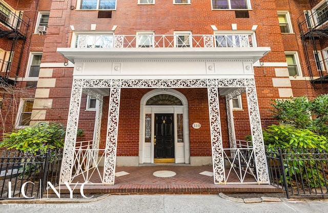 doorway to property with brick siding and fence