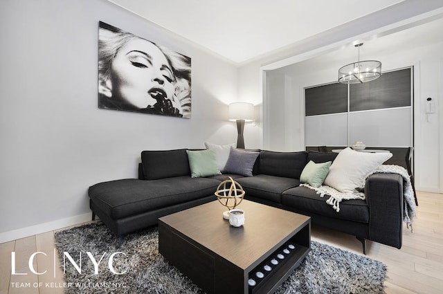 living area featuring an inviting chandelier, baseboards, and light wood finished floors