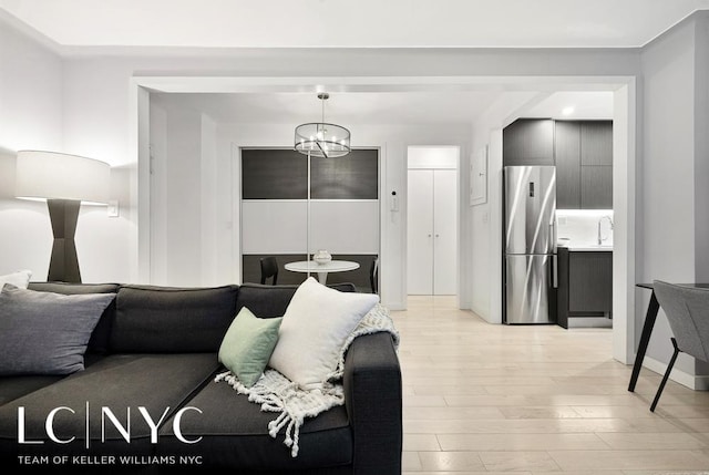 living area featuring baseboards, light wood finished floors, and a chandelier