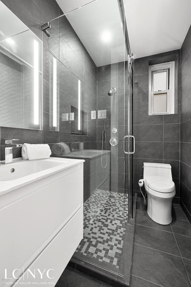 full bath with vanity, a stall shower, tile patterned flooring, tile walls, and toilet