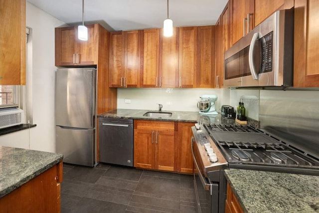 kitchen with a sink, decorative light fixtures, stainless steel appliances, dark stone counters, and brown cabinetry