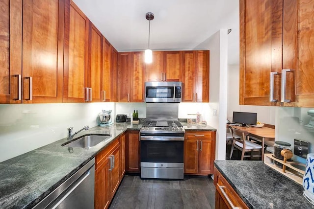 kitchen with dark stone countertops, brown cabinets, stainless steel appliances, and a sink