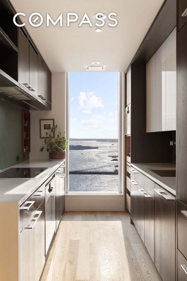 252 S St Unit 43C, New York City, NY 10002 - kitchen featuring black electric cooktop, modern cabinets, light countertops, light wood-style floors, and open shelves