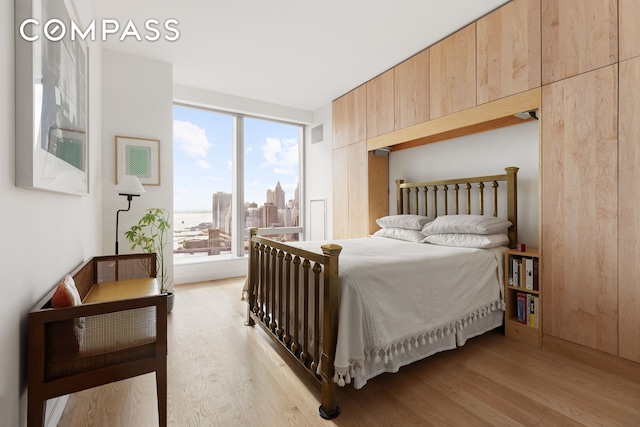 bedroom featuring a city view, visible vents, and light wood finished floors