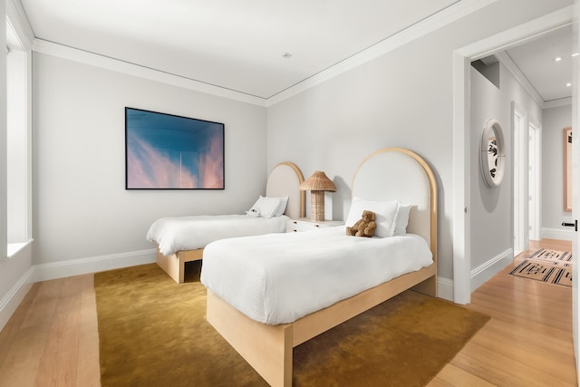 bedroom with crown molding, wood finished floors, and baseboards