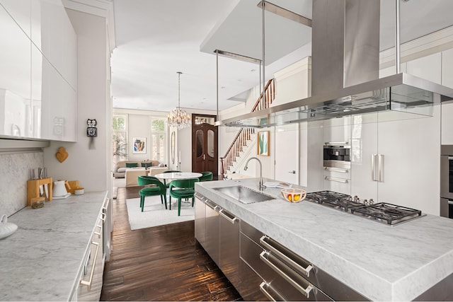 kitchen with a center island with sink, a sink, appliances with stainless steel finishes, exhaust hood, and modern cabinets