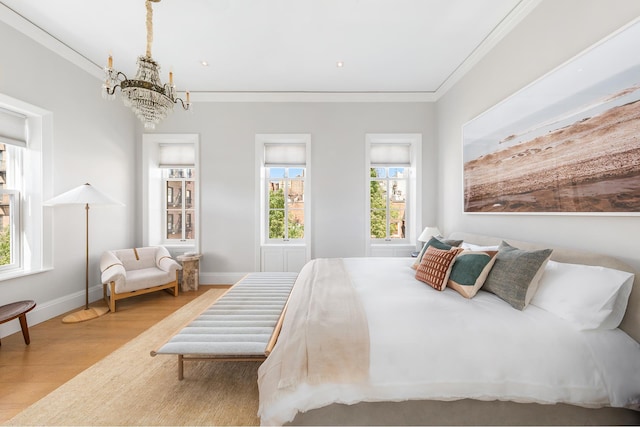 bedroom featuring baseboards, wood finished floors, a chandelier, and crown molding