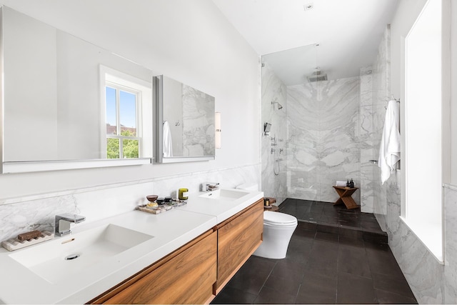 full bathroom featuring a sink, a marble finish shower, toilet, and tile walls