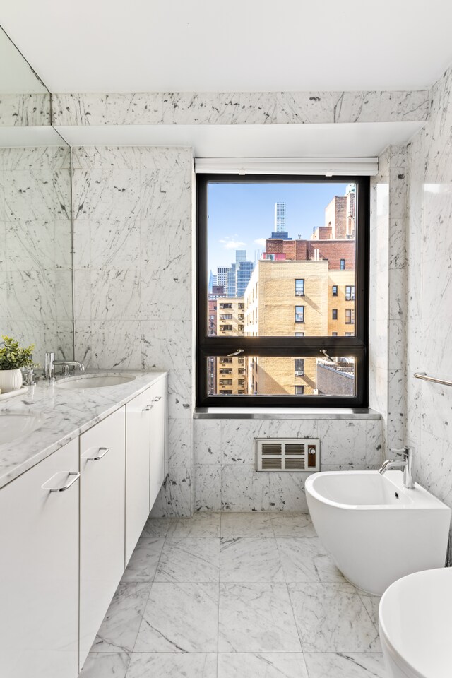 bathroom featuring a sink, a bidet, a city view, and marble finish floor