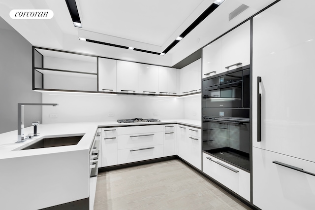 kitchen featuring visible vents, modern cabinets, a sink, gas cooktop, and white cabinets