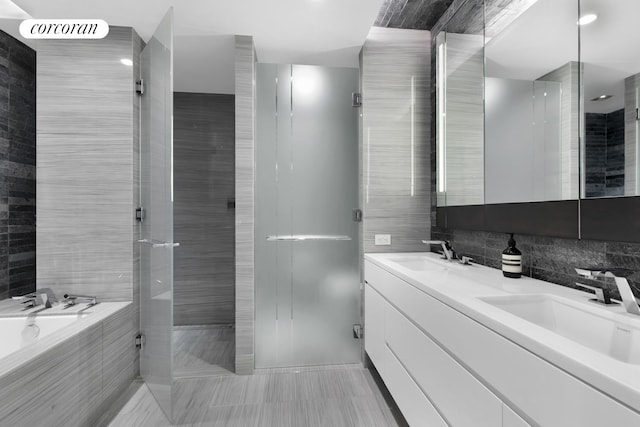 bathroom featuring tile walls, a garden tub, a walk in shower, and a sink