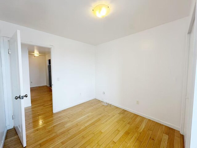 spare room featuring light wood-type flooring and baseboards