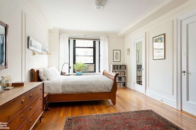 bedroom with wood finished floors and crown molding