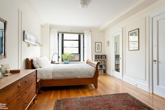 bedroom featuring ornamental molding and wood finished floors
