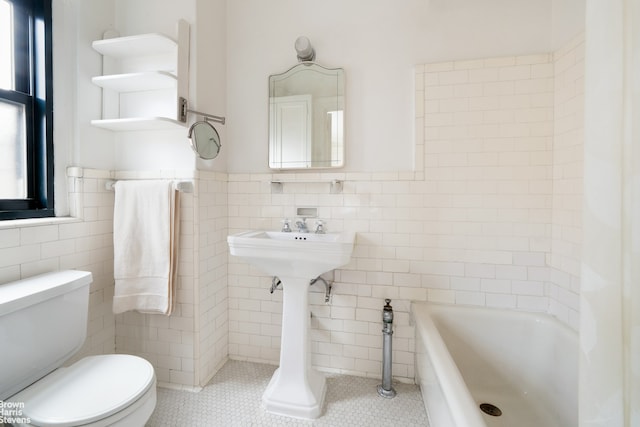 full bath featuring tile walls, toilet, tile patterned floors, and a washtub