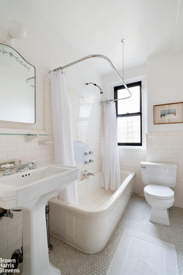 full bath with shower / bath combination with curtain, tile patterned flooring, toilet, wainscoting, and tile walls