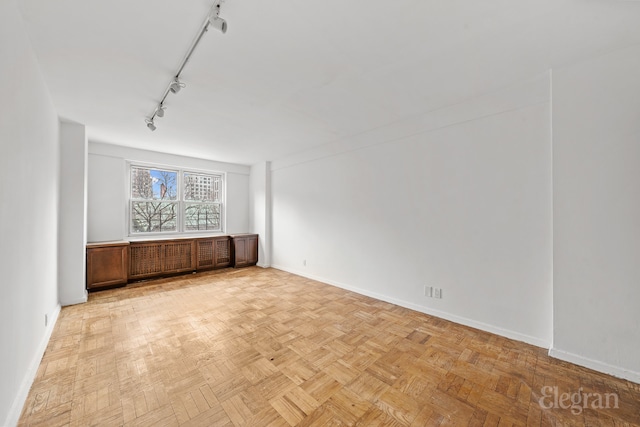 unfurnished dining area with rail lighting and baseboards