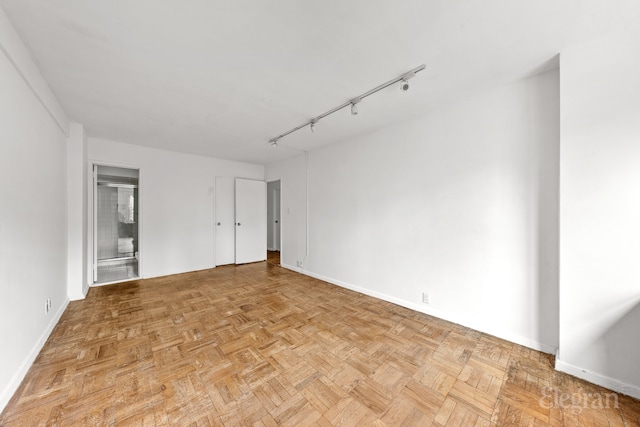 unfurnished room featuring baseboards and track lighting