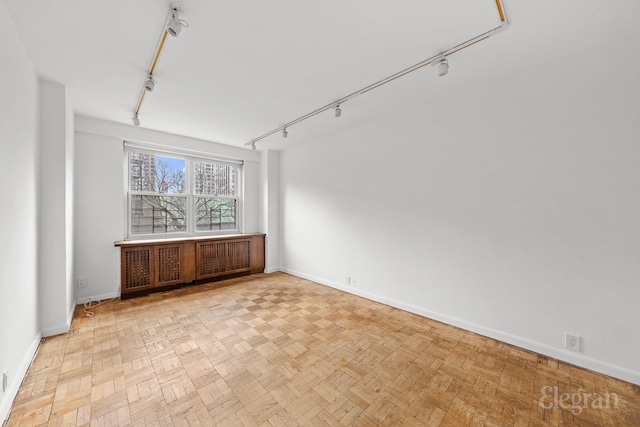 empty room with track lighting and baseboards