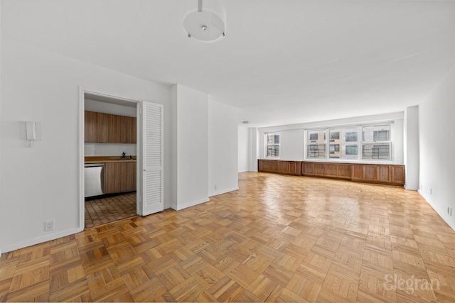 unfurnished living room with baseboards and a sink