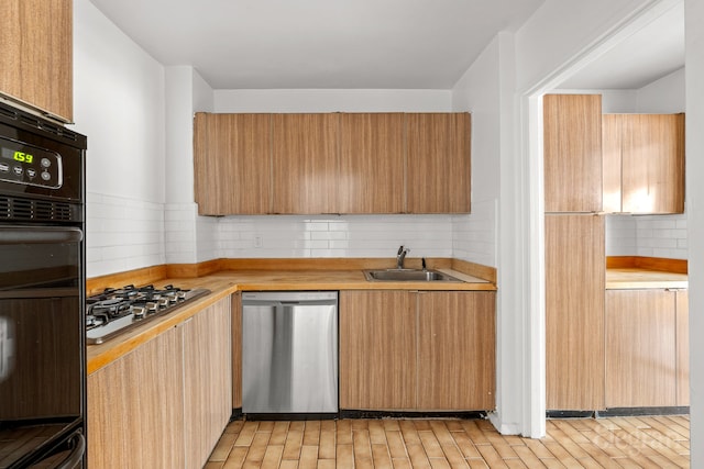 kitchen featuring stainless steel dishwasher, oven, backsplash, and a sink