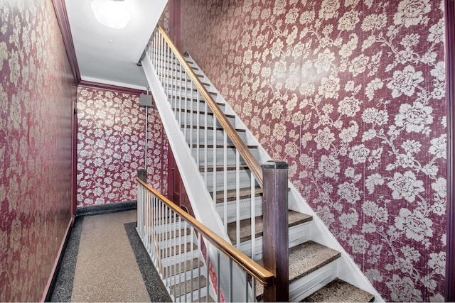 staircase featuring baseboards, crown molding, and wallpapered walls