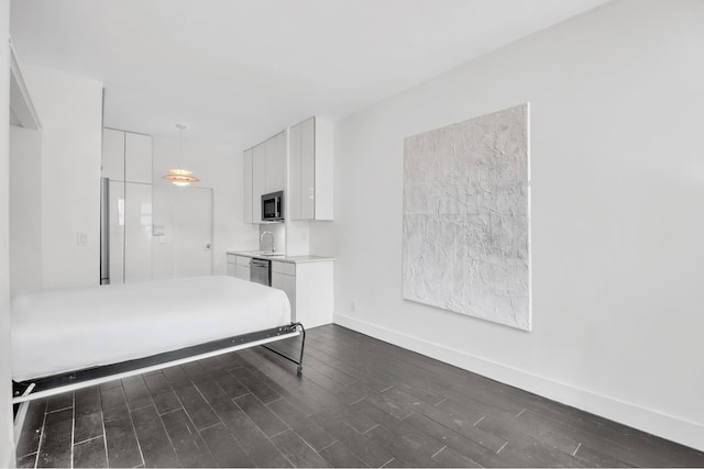 unfurnished bedroom with dark wood-type flooring, baseboards, and a sink