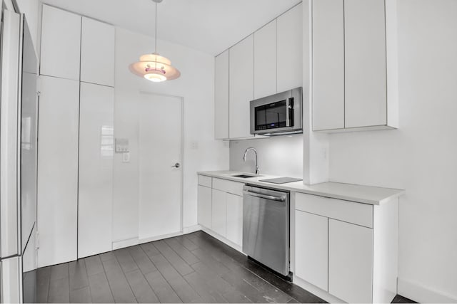 kitchen featuring decorative light fixtures, light countertops, appliances with stainless steel finishes, white cabinetry, and a sink